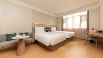 A hotel room with two beds, a sofa, a round table, and a desk.