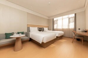 A hotel room with two beds, a sofa, a round table, and a desk. - Ji Hotel (Nanjing)