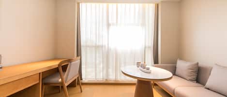 Uma sala de estar moderna com uma escrivaninha de madeira, uma mesa redonda e um sofá.