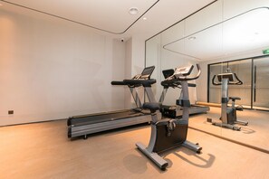 Uma academia moderna com esteiras, bicicletas ergométricas e um espelho grande.
