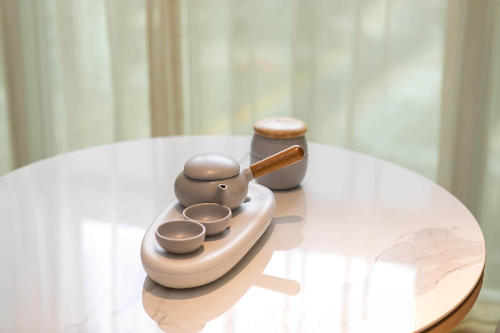 A round table with a tea set including a teapot, cups, and a small bowl.