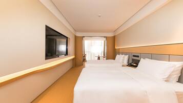 A hotel room with a large bed, a TV mounted on the wall, and a view of the hallway.