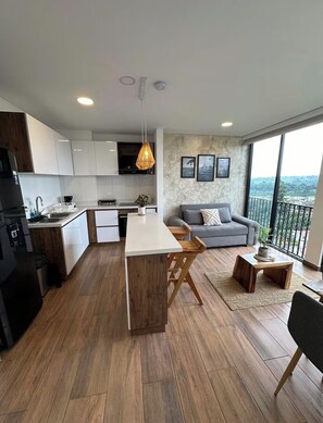A modern kitchen with a central island, a grey sofa, and a balcony with a view. - Cahove9 ; view and location (Armenia)