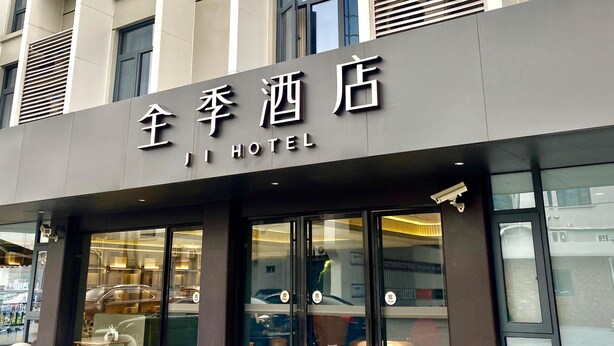 Un edificio de hotel con fachada moderna, ventanas grandes y un letrero que indica que es un hotel.