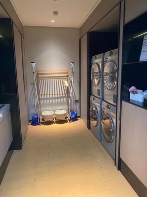 Un cuarto de lavandería con un tendedero, dos lavadoras y un aspirador.