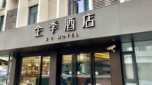 A hotel building with a modern facade, large windows, and a sign indicating it is a hotel.
