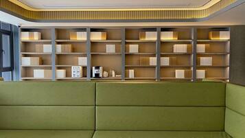 A modern library with a green sofa, bookshelves, and a ceiling with recessed lighting.