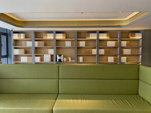 A modern library with a green sofa, bookshelves, and a ceiling with recessed lighting.