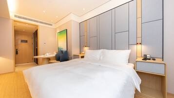 A hotel room with a large bed, bedside tables, a desk, and a painting on the wall.