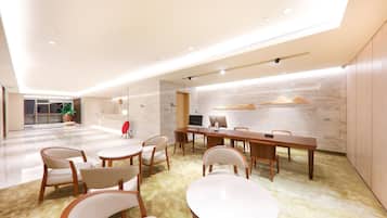 A modern conference room with a long table, chairs, a TV, and a plant.