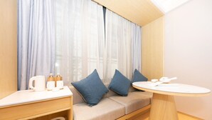 A modern room with a sofa, a small table, and a window with sheer curtains. - Ji Hotel (nanjing Confucius Temple Pedestrian Stre (Nanjing)