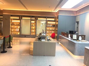 A modern hotel lobby with a central island, seating area, and a bookstore.