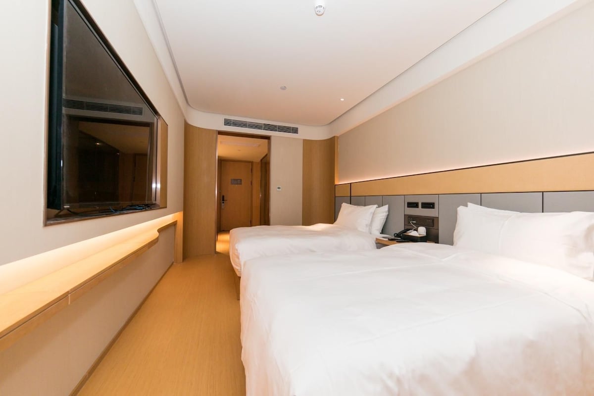 A hotel room with two beds, a bedside table, a telephone, and a mirror.