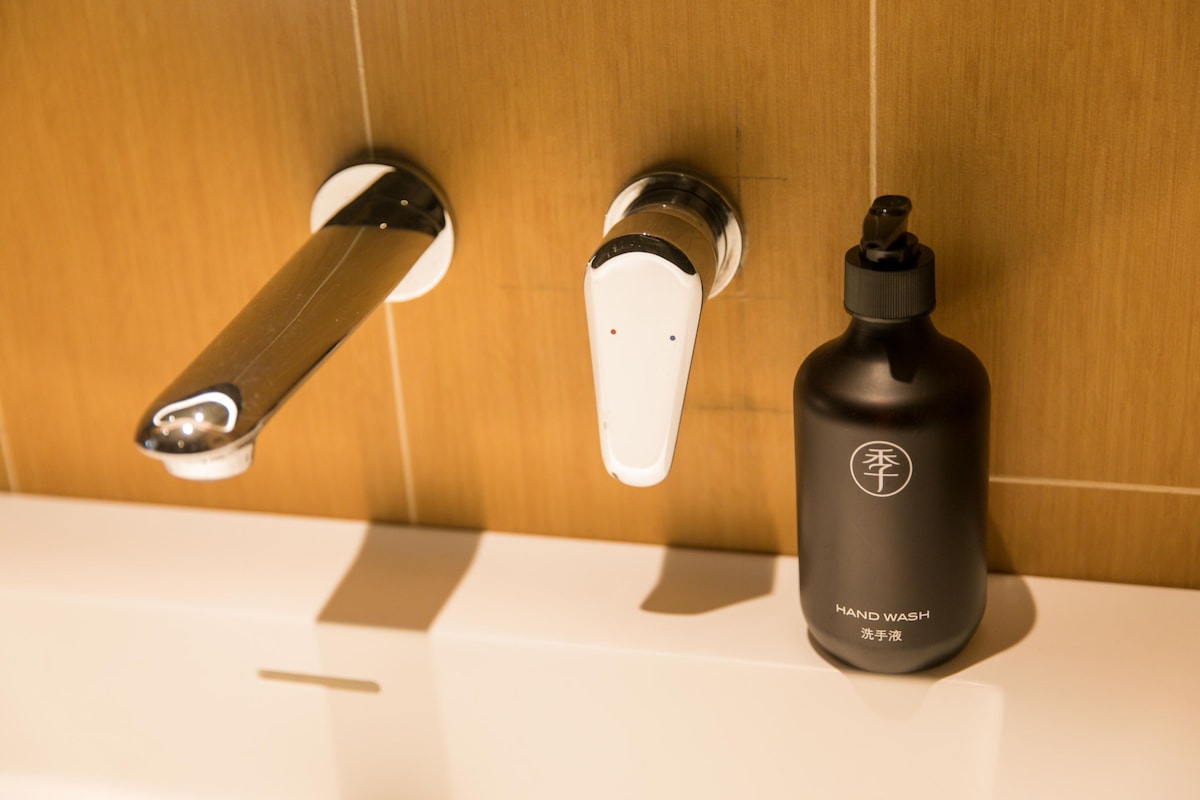 A bathroom with a modern faucet, a hand soap dispenser, and a white sink.