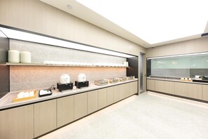A modern kitchen with a long counter, coffee machines, and storage containers. - Ji Hotel (Nanjing)