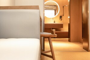 A modern hotel room with a wooden bed frame, a round mirror, and a wooden floor. - Ji Hotel (Nanjing)