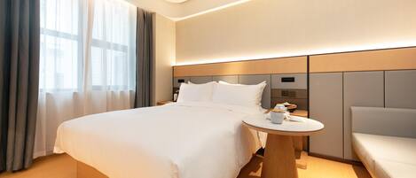 A hotel room with a large bed, bedside table, and a small seating area.