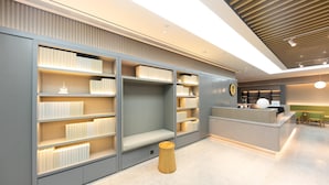 A modern library with bookshelves, a reception desk, and a wooden stool. - Ji Hotel (Nanjing)