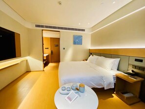 Een hotelkamer met een bed, nachtkastje en een klein rond tafeltje met een dienblad.