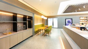 A modern interior with a reception desk, seating area, and a television screen. - Ji Hotel (Nanjing)