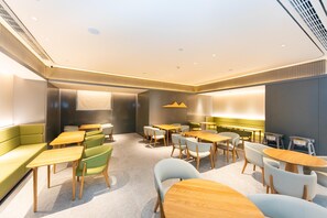 A modern conference room with a green sofa, wooden tables, and chairs. - Ji Hotel (Nanjing)
