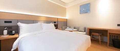 A modern hotel room with a large bed, bedside tables, a desk, and a chair.