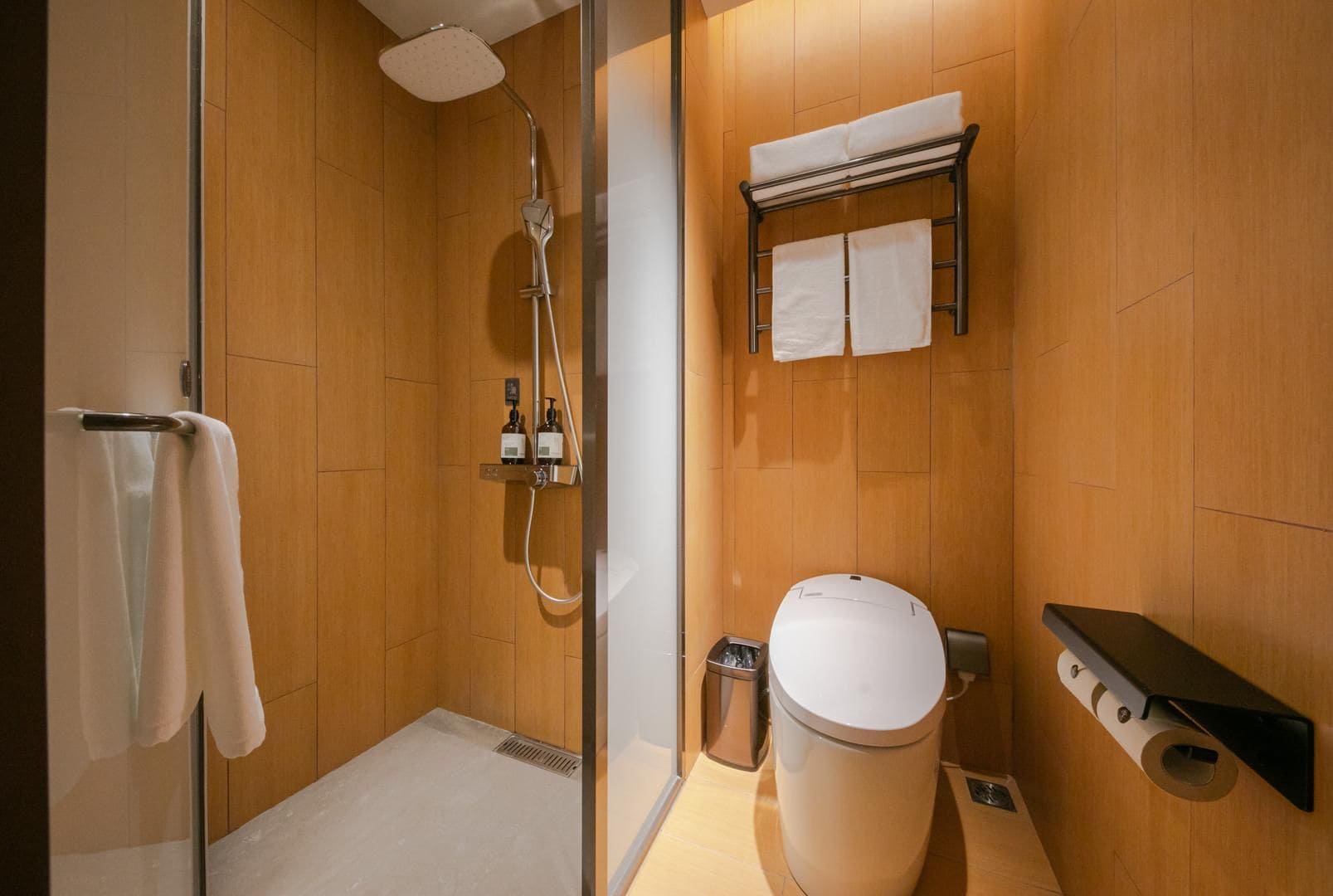 A modern bathroom with a shower, toilet, and towel rack.