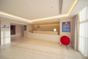 Zona de recepción de un hotel con diseño moderno, que incluye un mostrador de recepción, un reloj y señalización informativa.
