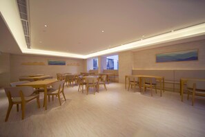A spacious room with multiple tables and chairs, a high ceiling with recessed lighting, and artwork on the walls. - Ji Hotel (renmin University Of China Metro Station (Beijing)