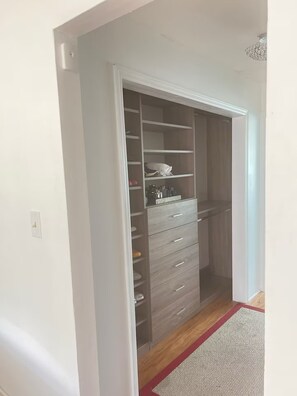 Ein begehbarer Kleiderschrank mit mehreren Regalen und Schubladen, ein Holzboden und ein roter Teppich.