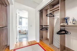 A modern interior with a wooden floor, a hallway leading to a room, and a closet with hangers and a patterned item. - Private Oasis Bungalow (Orlando)