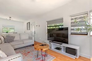 A modern living room with a sofa, a coffee table, a TV, and a plant. - Private Oasis Bungalow (Orlando)