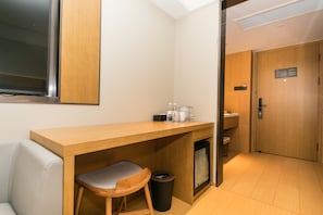 A compact hotel room with a kitchenette, a small trash bin, a seating area, and a door leading to another room. - Ji Hotel (Nanjing)