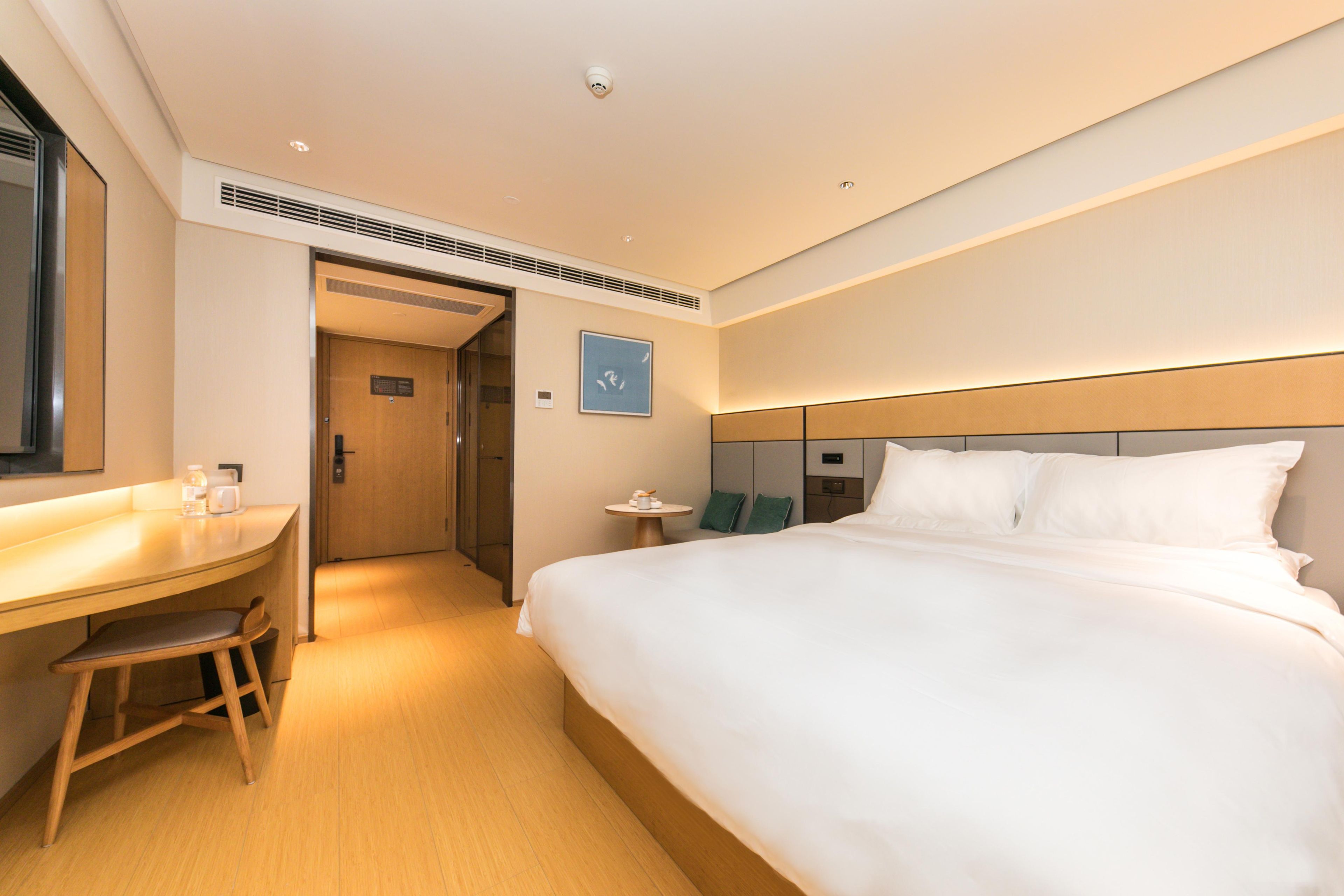 A hotel room with a bed, a desk, a chair, and a small table.