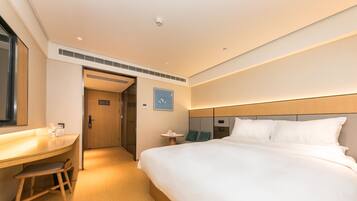 A hotel room with a bed, a desk, a chair, and a small table.