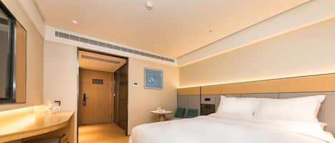 Una habitación de hotel con cama, escritorio, silla y una pequeña mesa.
