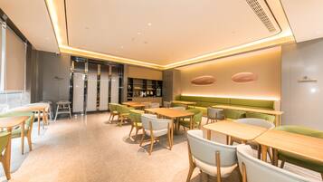 A modern dining area with tables and chairs, a counter, and a seating area with a green upholstered bench.