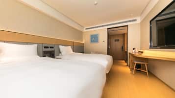A hotel room with two beds, a desk, and a mirror.