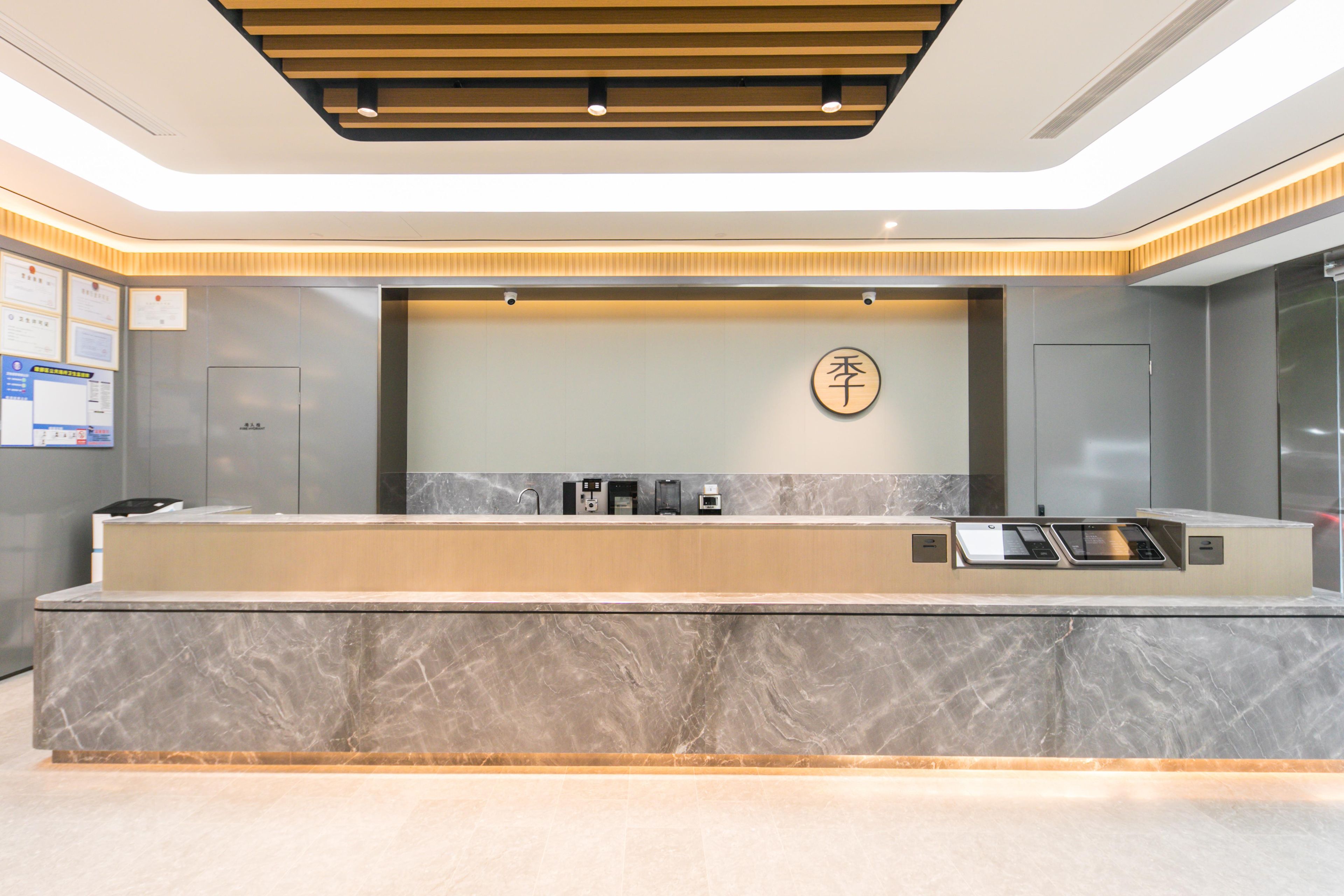 A modern reception desk with a marble countertop, a digital screen, and a wall-mounted sign.