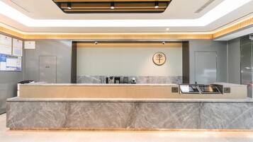 A modern reception desk with a marble countertop, a digital screen, and a wall-mounted sign.