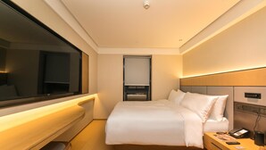 A modern hotel room with a large bed, bedside table, and a TV. - Ji Hotel (Nanjing)