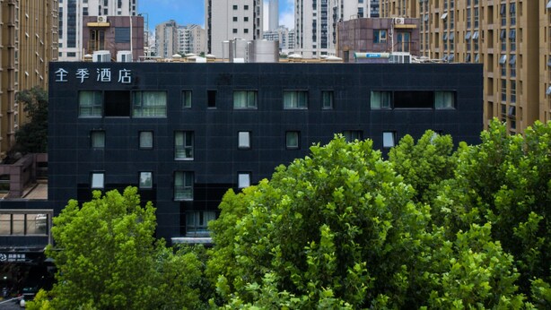 A modern hotel building with a dark facade, multiple windows, and a sign in a foreign language. - Ji Hotel (Nanjing)
