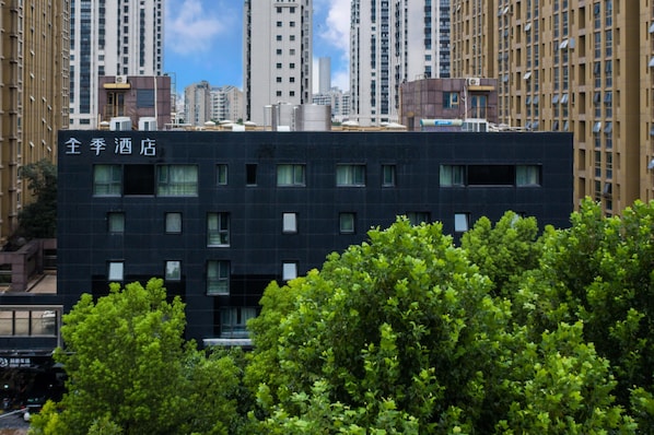A modern hotel building with a dark facade, multiple windows, and a sign in a foreign language. - Ji Hotel (Nanjing)