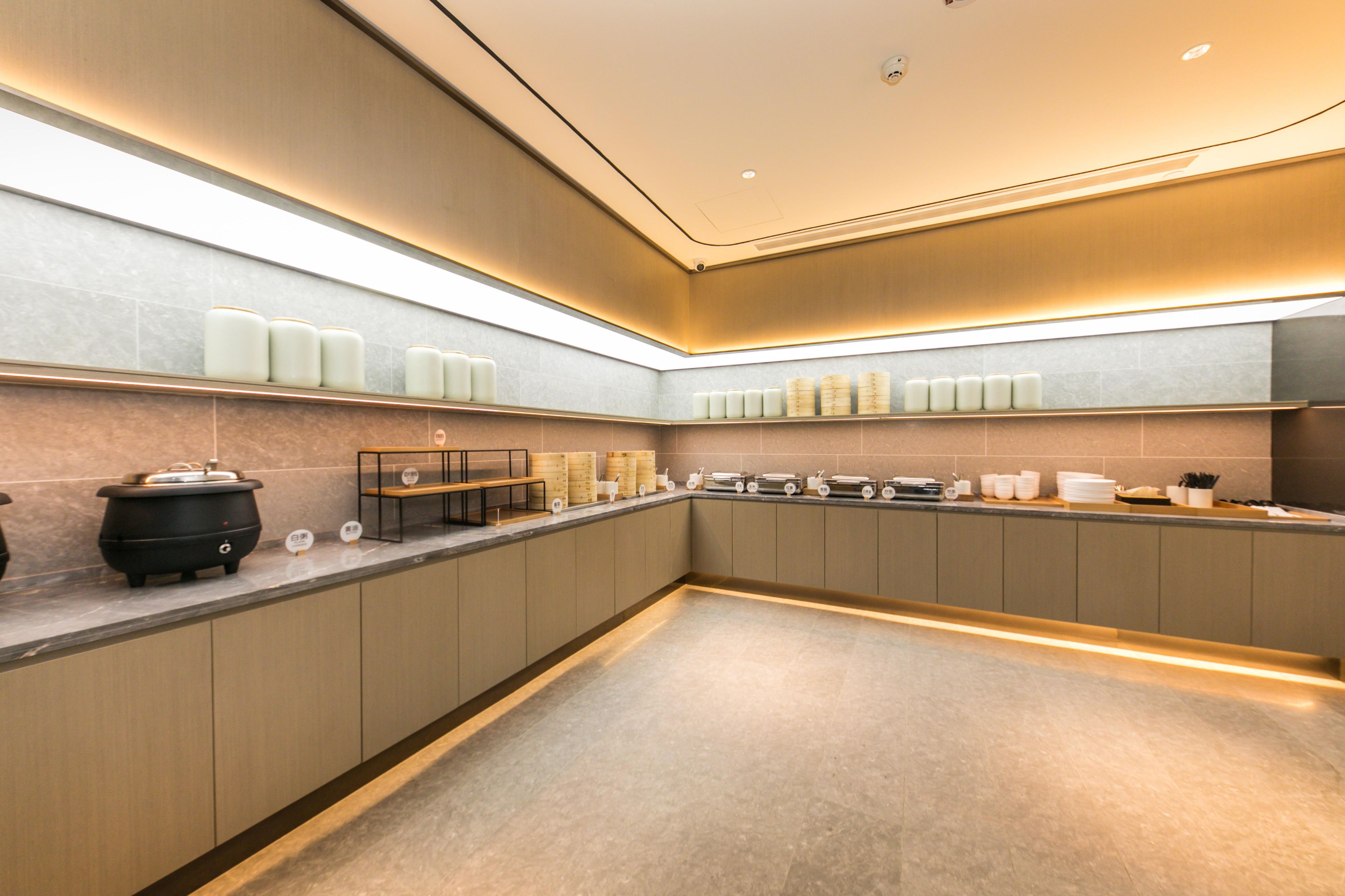 A modern kitchen with a long countertop, built-in cabinets, and a pot on the left.