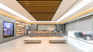 A modern reception area with a marble counter, wooden ceiling, and a digital display on the left. - Ji Hotel (Nanjing)