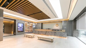 A modern reception area with a marble counter, wooden benches, and a digital display. - Ji Hotel (Nanjing)