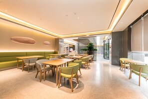 A modern restaurant interior with green seating, wooden tables, and a bright, well-lit ambiance. - Ji Hotel (Nanjing)