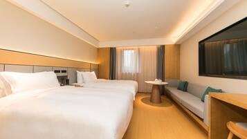 Een hotelkamer met een groot bed, een slaapbank, een tafeltje en een aan de muur bevestigde televisie.