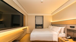A modern hotel room with a large bed, bedside table, and a TV. - Ji Hotel (Nanjing)