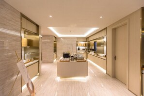 A modern hotel lobby with a central reception desk, a large mirror, and a minimalist design.